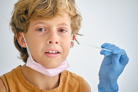 Crop nurse with swab touching face of crying boy photo