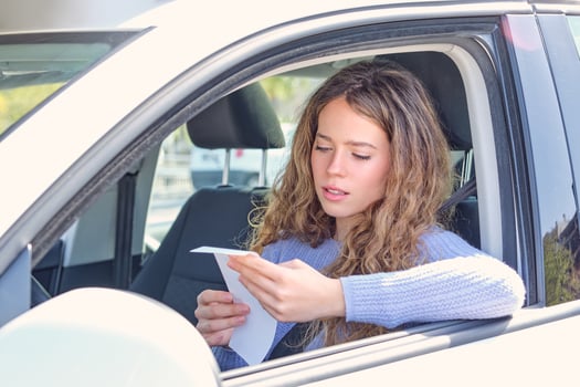 Young woman reading penalty receipt in car drivers seat photo