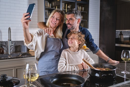 Cheerful diverse family taking selfie on mobile phone in kitchen photo