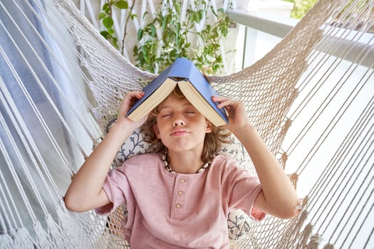 Boy with book on head lying in hammock photo