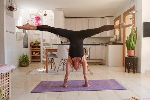Sportswoman taking Handstand pose with legs apart at home photo