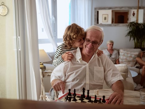 Tender grandson hugging grandfather playing chess game photo