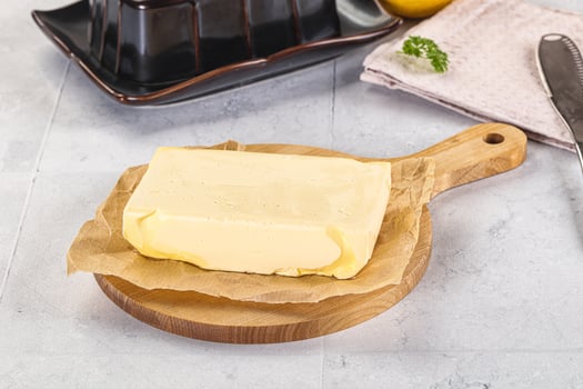 A piece of butter on a cutting board next to a knife photo