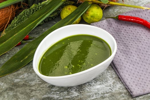 A bowl of green sauce next to a bowl of chili peppers photo