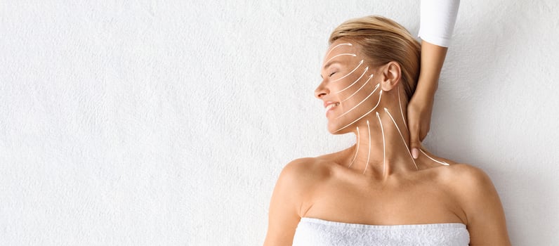 Middle aged woman receives a soothing facial massage from a professional. She relaxes with eyes closed, enjoying pampering experience focused on skin rejuvenation and anti-aging benefits, copy space photo