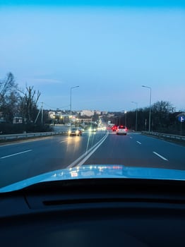 Evening road traffic with cars driving towards the city under a bright sky. photo