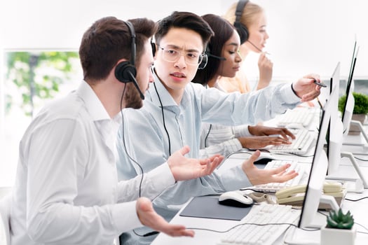 User support service concept. Hotline operator helping his coworker at call centre. Customer care agents communicating to each other, solving client's problem at modern office photo