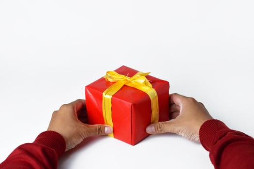A Man Dressed in Red Presents a Red Gift Box photo