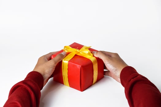 A Mans Hand Wrapped in Red Sweater Holds a Red Gift photo