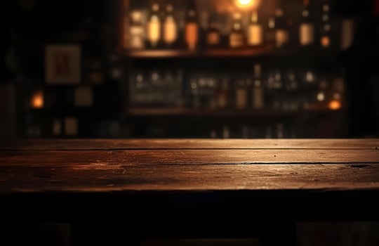 A wooden table in front of a bar photo