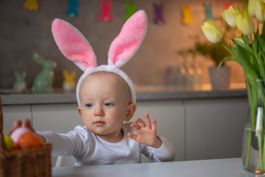 happy cute little baby girl wearing bunny ears on easter day sitting at the table in the kitchen photo