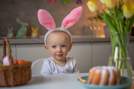 happy cute little baby girl wearing bunny ears on easter day sitting at the table in the kitchen photo