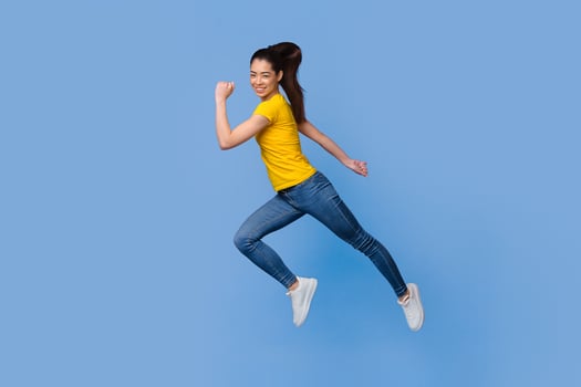 Time To Move. In Motion Portrait Of Happy Asian Girl Jumping In The Air Over Purple Background, Full-Length Shot With Copy Space photo