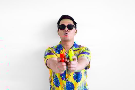 Thai male holding blurred focus of water guns wearing colorful shirt for Thailand Songkran festival concept. photo