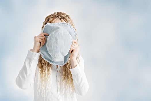 Woman holding sun hat in front of face, blue gradient background, summer and vacation minimal concept. Female with long hair dreadlocks hiding behind blue bucket hat. Creative portrait photo. photo