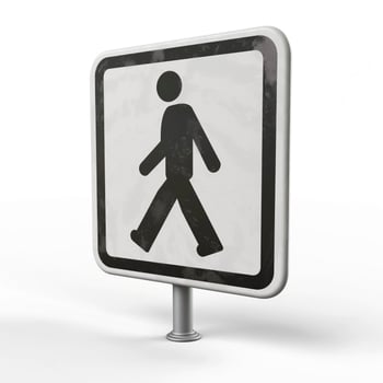 A walking symbol on a weathered pedestrian sign, suggesting a pedestrian-friendly area. photo