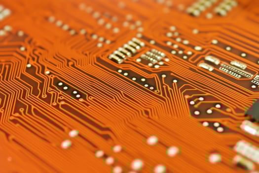 Close up of an orange circuit board showcasing the detailed lines and connections. photo