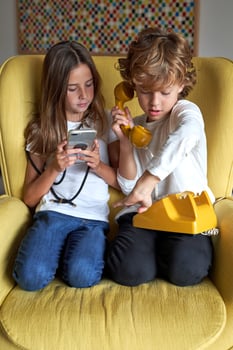 Girl with smartphone near boy with retro telephone photo