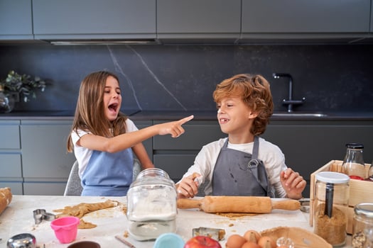 Girl with mouth opened pointing at nose of boy photo