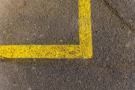 Yellow painted corner line on a concrete surface indicating a parking space near a busy urban area photo
