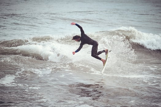 Surfer male jumping on wave standing on surfboard in ocean photo