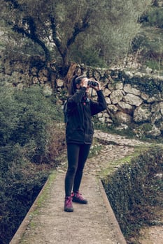 Female hiker using binoculars during trekking in forest photo