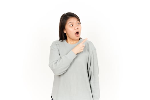 A woman in a grey sweatshirt pointing to her mouth photo