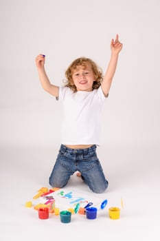 Excited boy near colorful paints photo