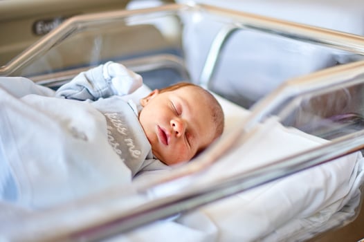 Newborn baby sleeping in its hospital crib photo