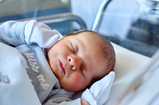 Newborn baby sleeping in its hospital crib photo