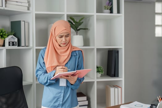 Muslim woman in hijab taking notes from documents in modern office. photo