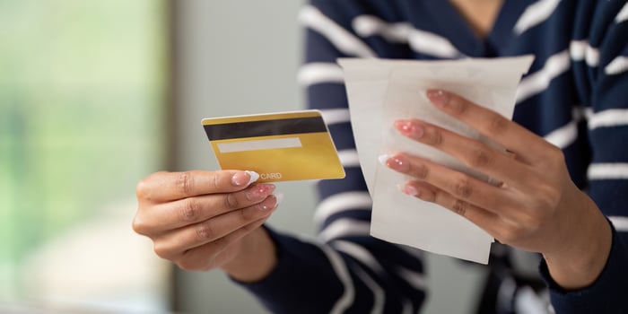 Woman holding credit card and bills, assessing her financial situation. photo