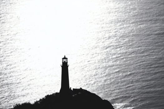 Lighthouse watches over calm waters AI photo
