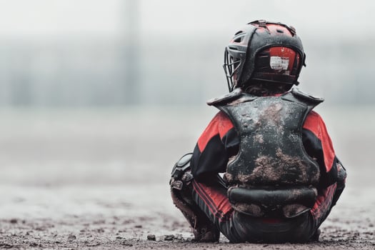 Young baseball player sits on muddy field photo
