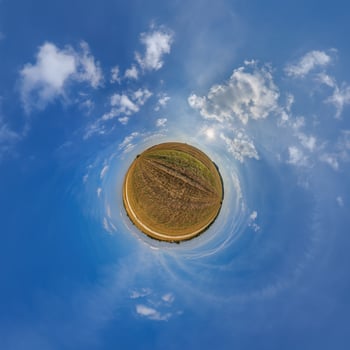 A small planet with a blue sky and clouds photo