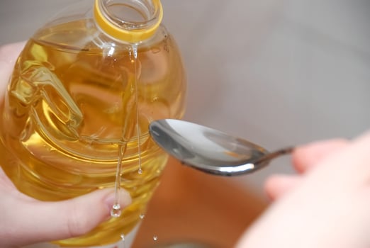 Pouring Oil from Bottle into Spoon photo