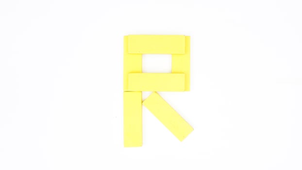Yellow color wood block formed into letter R isolated on white background photo