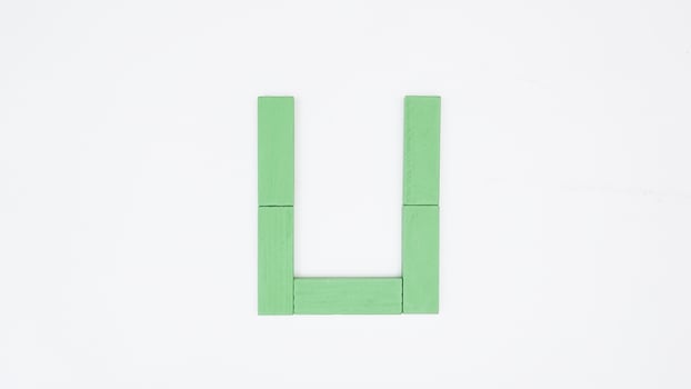 Letter U from green color wood block isolated on white background photo