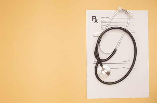 Top view of a stethoscope over the medical prescription sheet on an orange background photo