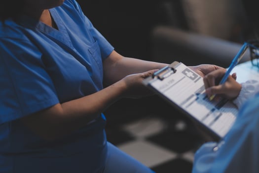 A nurse is holding a clipboard while another person is holding a pen photo
