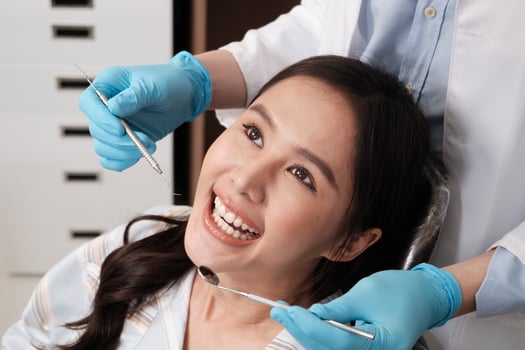 Close-up shot of Asian woman face, beautiful white teeth, and cheerful face in dentist's hand, dental treatment with tooth whitening and cleaning in doctor hospital clinic, oral hygiene healthcare. photo
