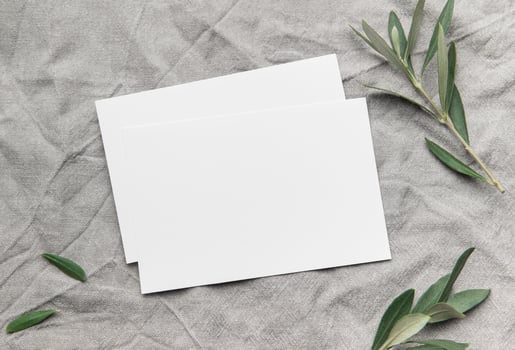Blank cards with olive branches resting on gray linen fabric photo