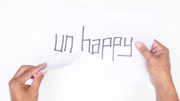 Man hands tearing letters UN from word UNHAPPY isolated on white background photo