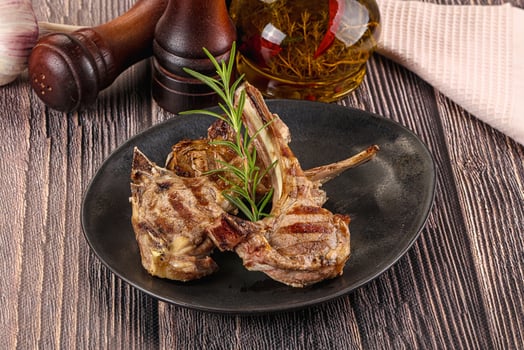 Grilled lamb chops on a black plate with herbs photo