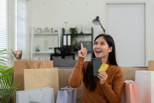 Shopping ideas. Woman pondering while holding credit cards and sitting with shopping bags. photo