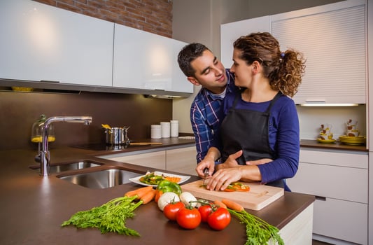 Couple hugging and preparing vegetables in the kitchen photo