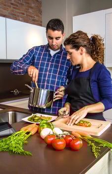 Woman cutting vegetables and man showing pot photo