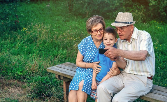 Grandparents and grandson taking selfie sitting on a bench photo