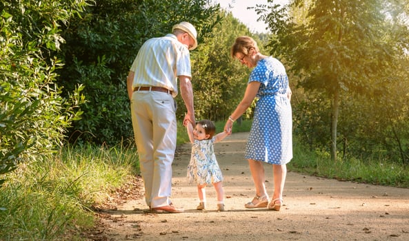 An older man and woman holding hands with a little girl photo