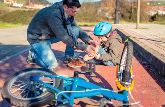 Father putting plaster band over knee injury to his son photo